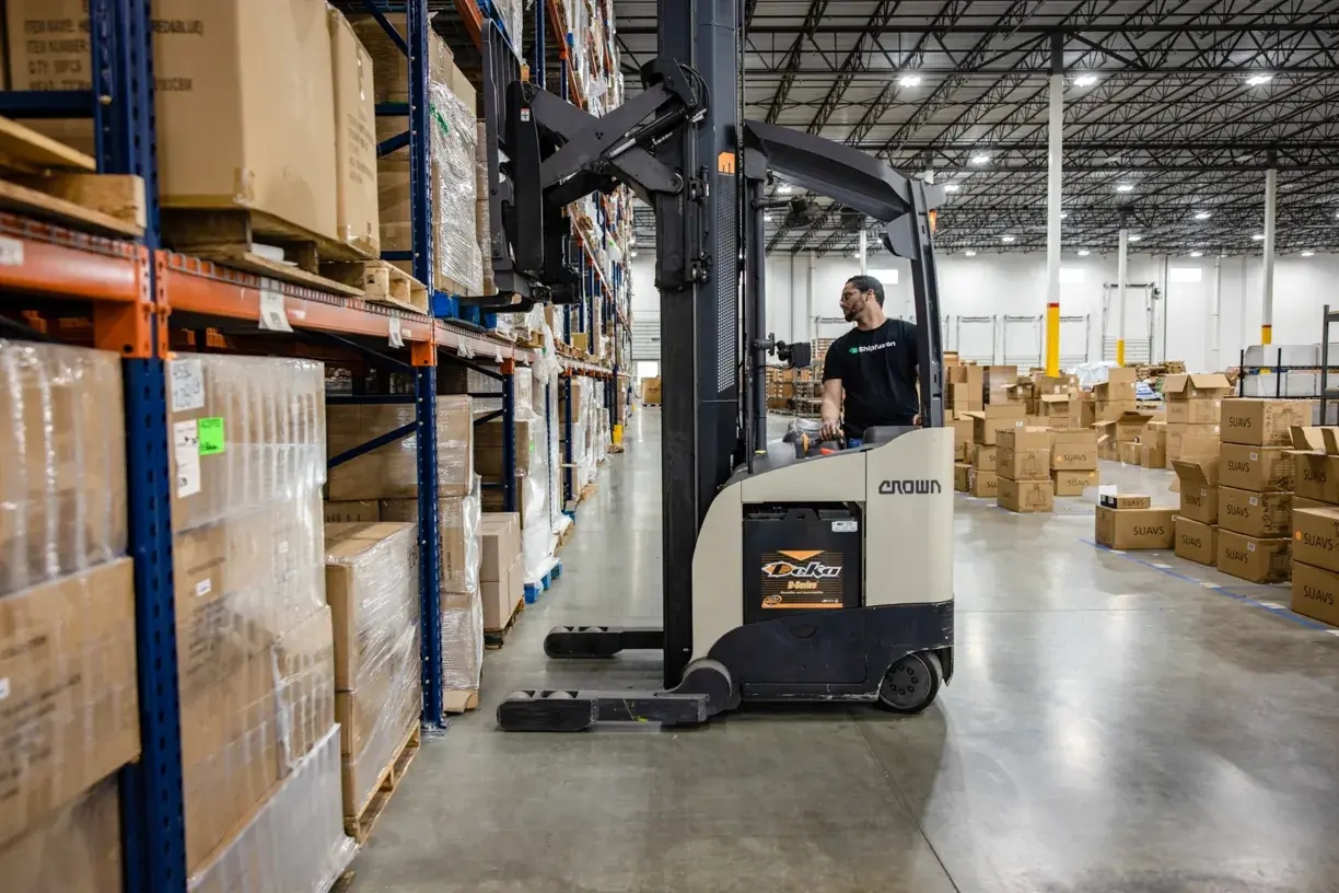 A Shipfusion reach-truck operator lifting a pallet into narrow-aisle racking